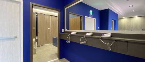 A modern bathroom with blue walls, a wooden floor, and a mirror with a vanity.