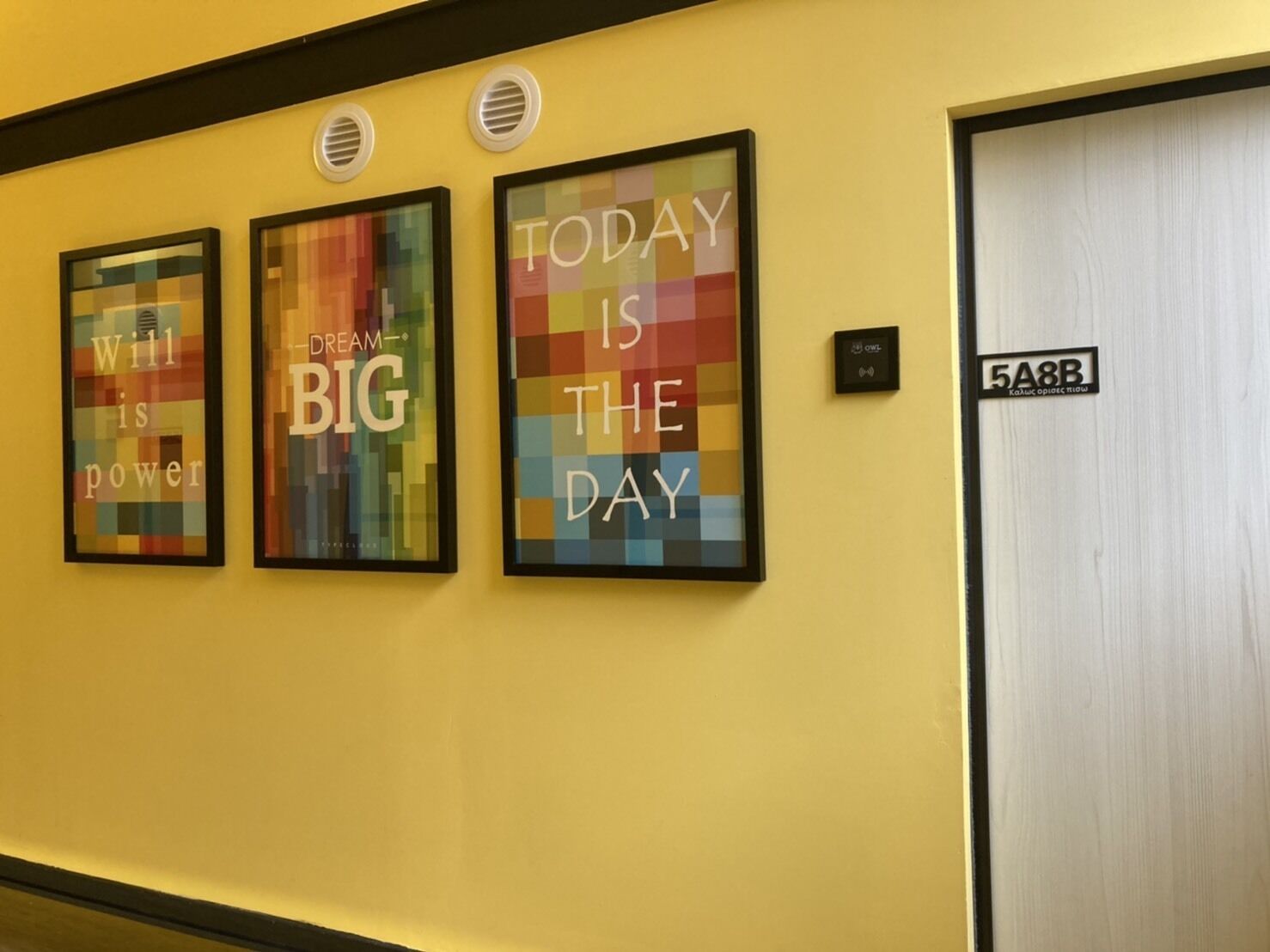 A hallway with three motivational posters on the wall and a door labeled "5A8B".