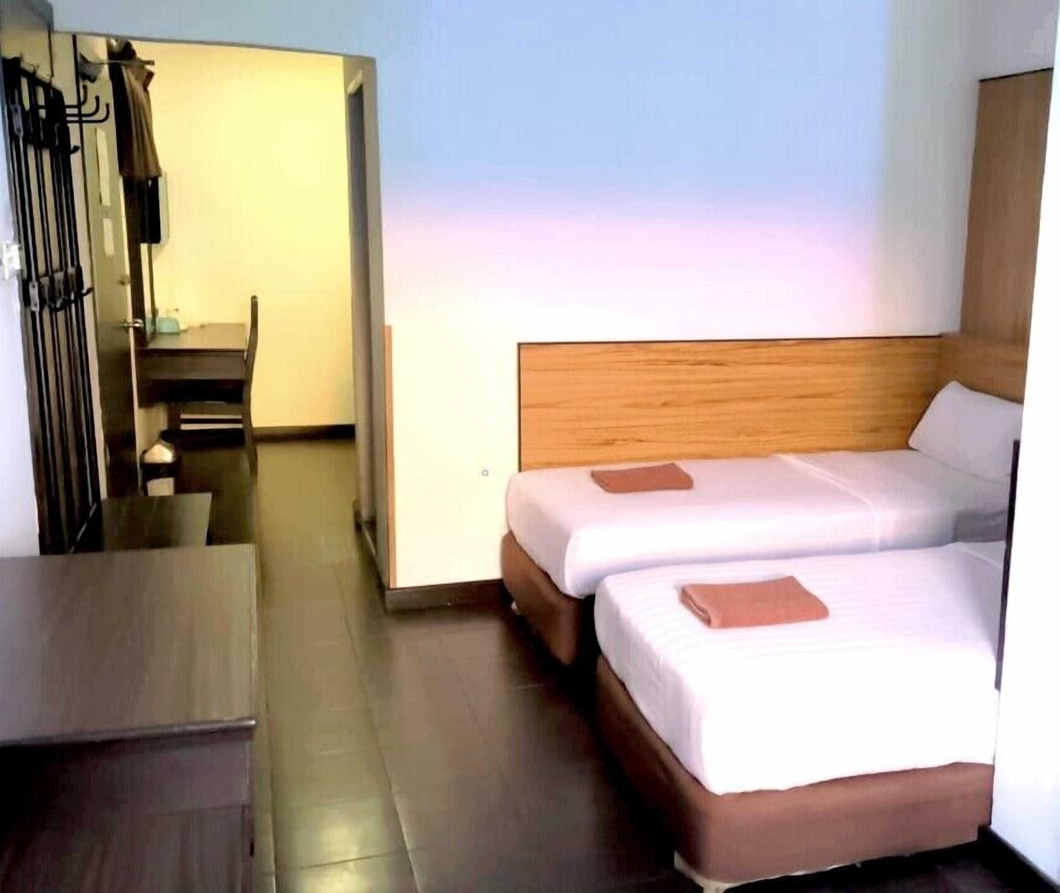 A hotel room with two beds, a wooden headboard, a small table, and a chair.