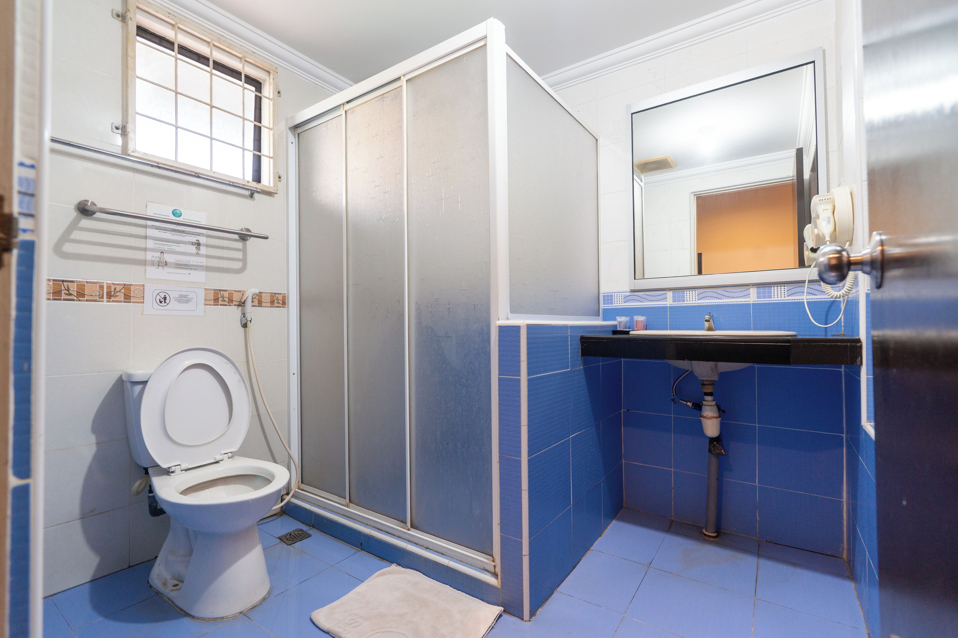 A bathroom with a toilet, a shower enclosure, a sink, and a mirror.