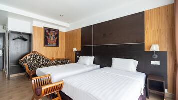 Une chambre d’hôtel avec deux lits, un banc en bois, un canapé et une petite table.