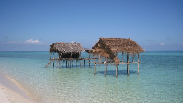 Two thatched-roof huts on stilts over clear turquoise water. - Sipadan Inn 2 (Semporna)