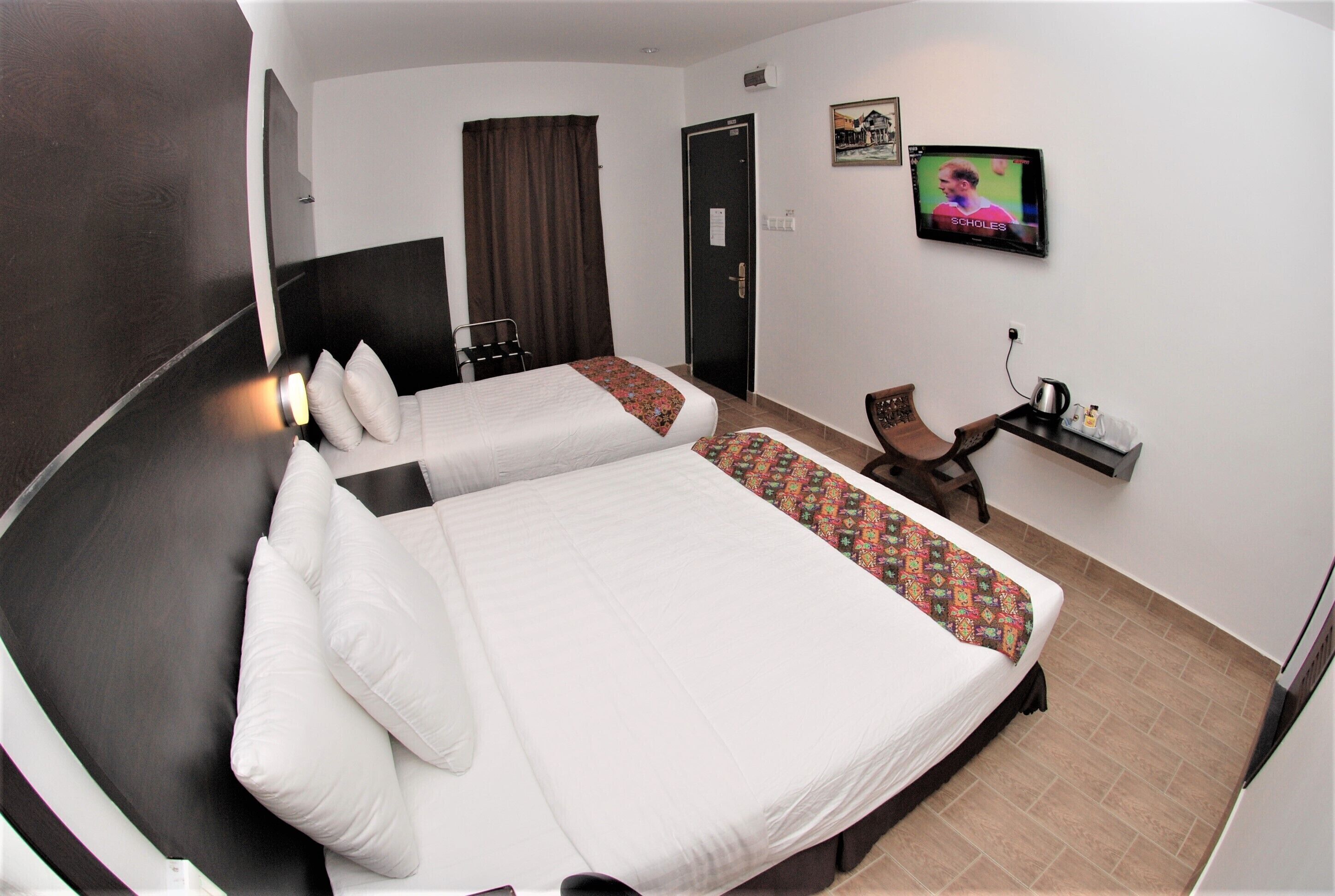 Ein Hotelzimmer mit einem großen Bett, einem Schreibtisch, einem Sessel, einem Fernseher und einer Tür.