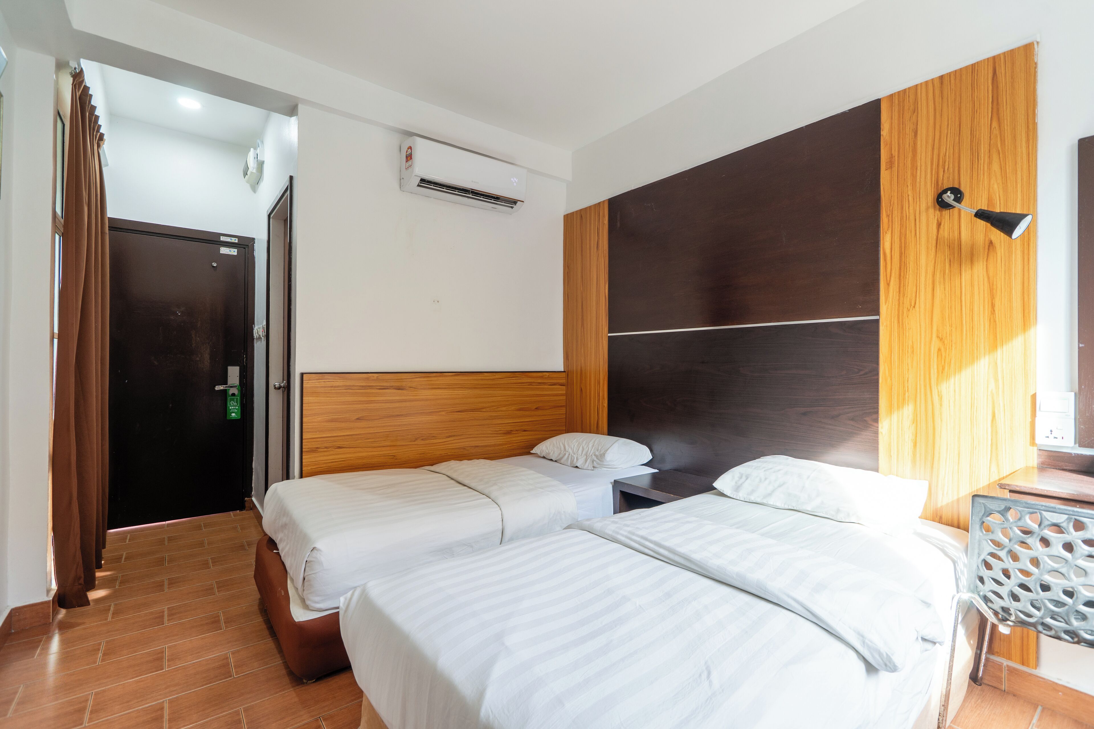 A hotel room with two beds, a wooden headboard, a nightstand, and a desk with a chair.