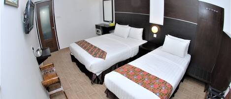 A hotel room with two beds, a desk, a chair, a mirror, and a TV.