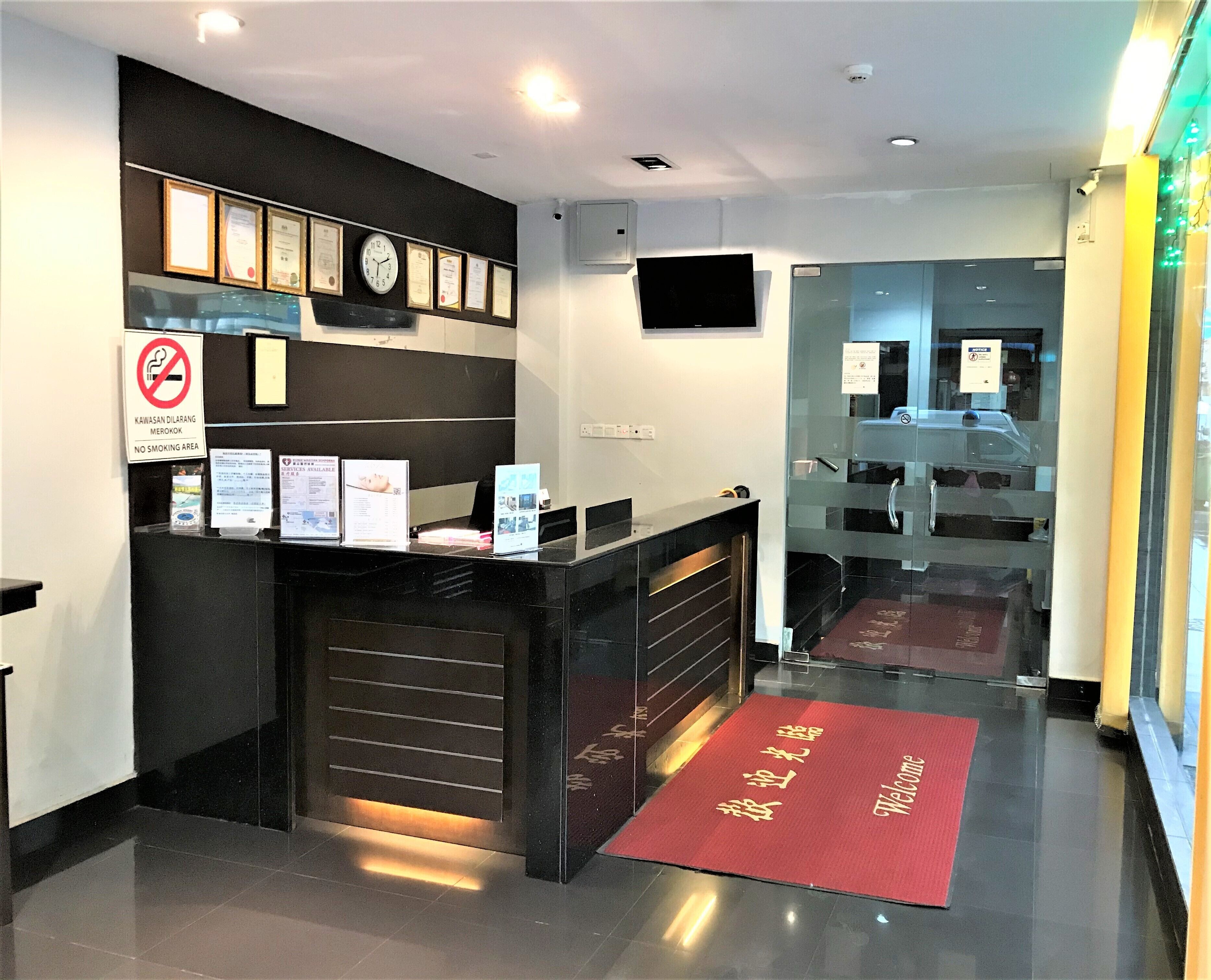A reception desk with framed certificates, a no-smoking sign, and a welcome mat.