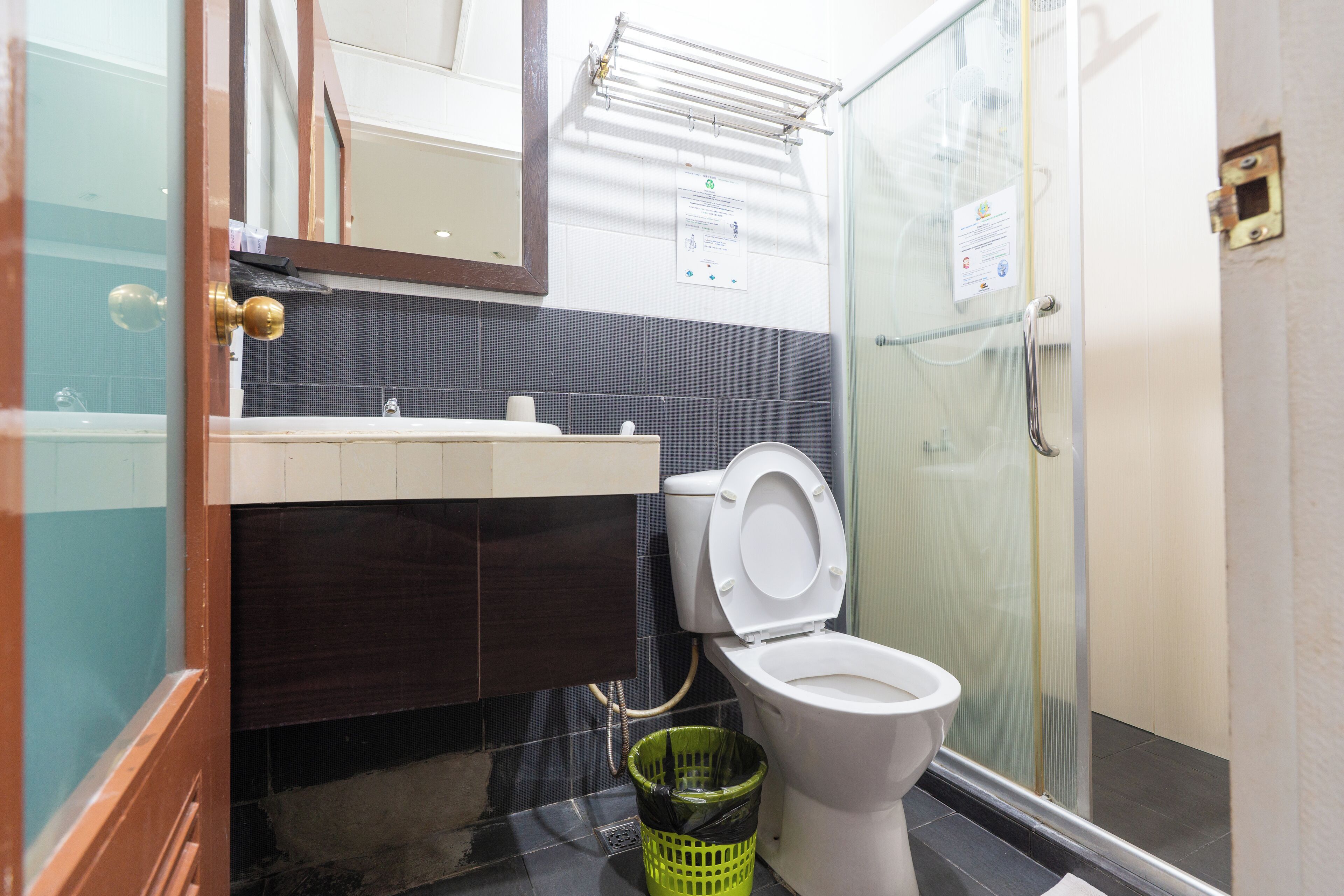 A bathroom with a toilet, a sink, a mirror, and a shower area.