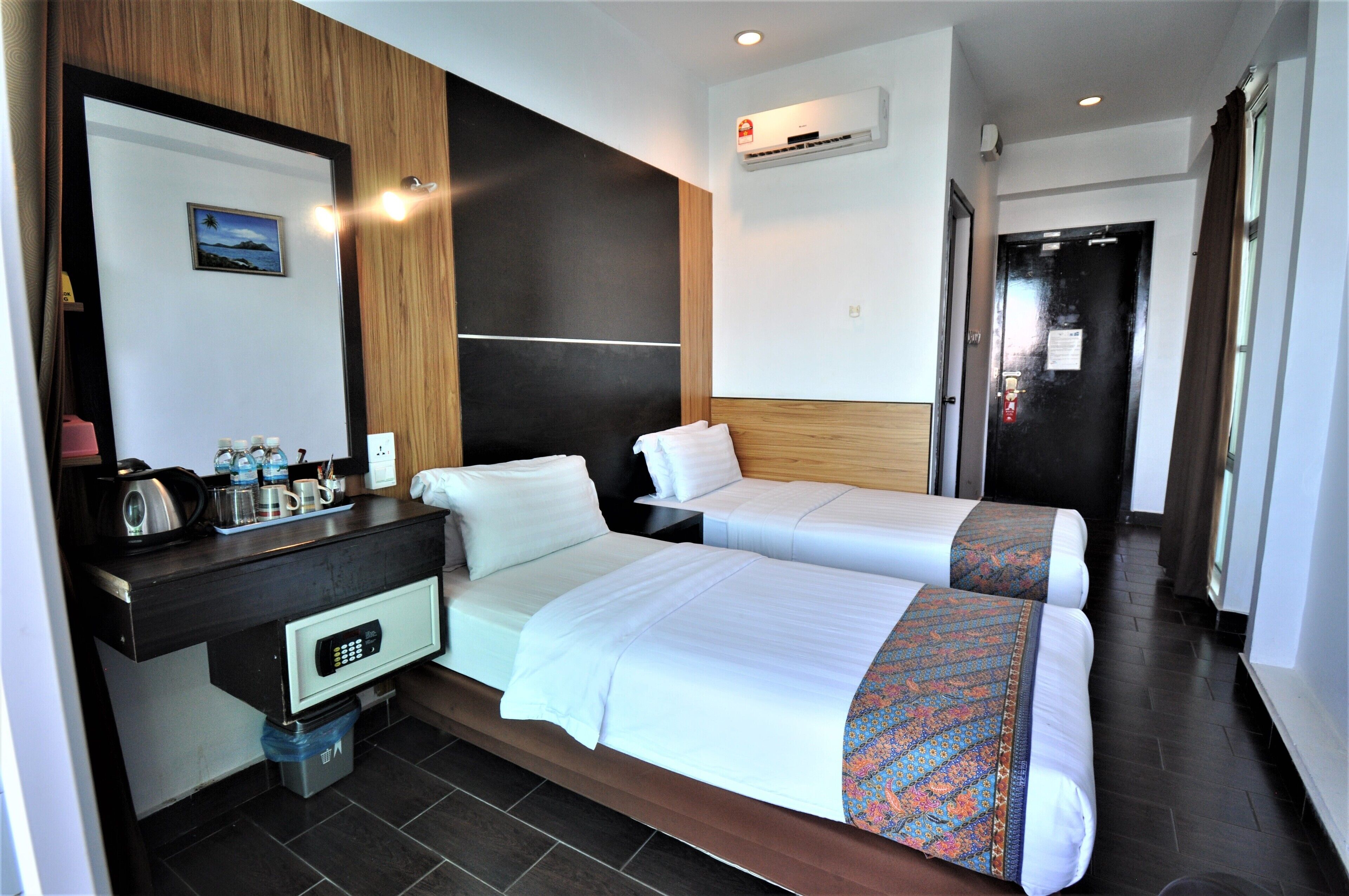 A hotel room with two beds, a desk with a coffee maker, and a small trash bin.