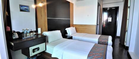A hotel room with two beds, a desk with a coffee maker, and a small trash bin.