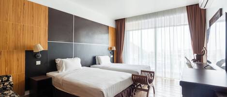 A hotel room with two beds, a desk, a chair, and a TV.