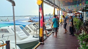 A covered deck with a view of boats and a restaurant area. - Sipadan Inn 2 (Semporna)