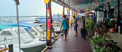 A covered deck with a view of boats and a restaurant area.