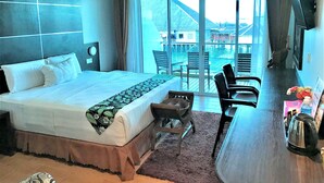 A hotel room with a bed, a desk, a chair, a coffee maker, and a view of a water body. - Sipadan Inn 2 (Semporna)