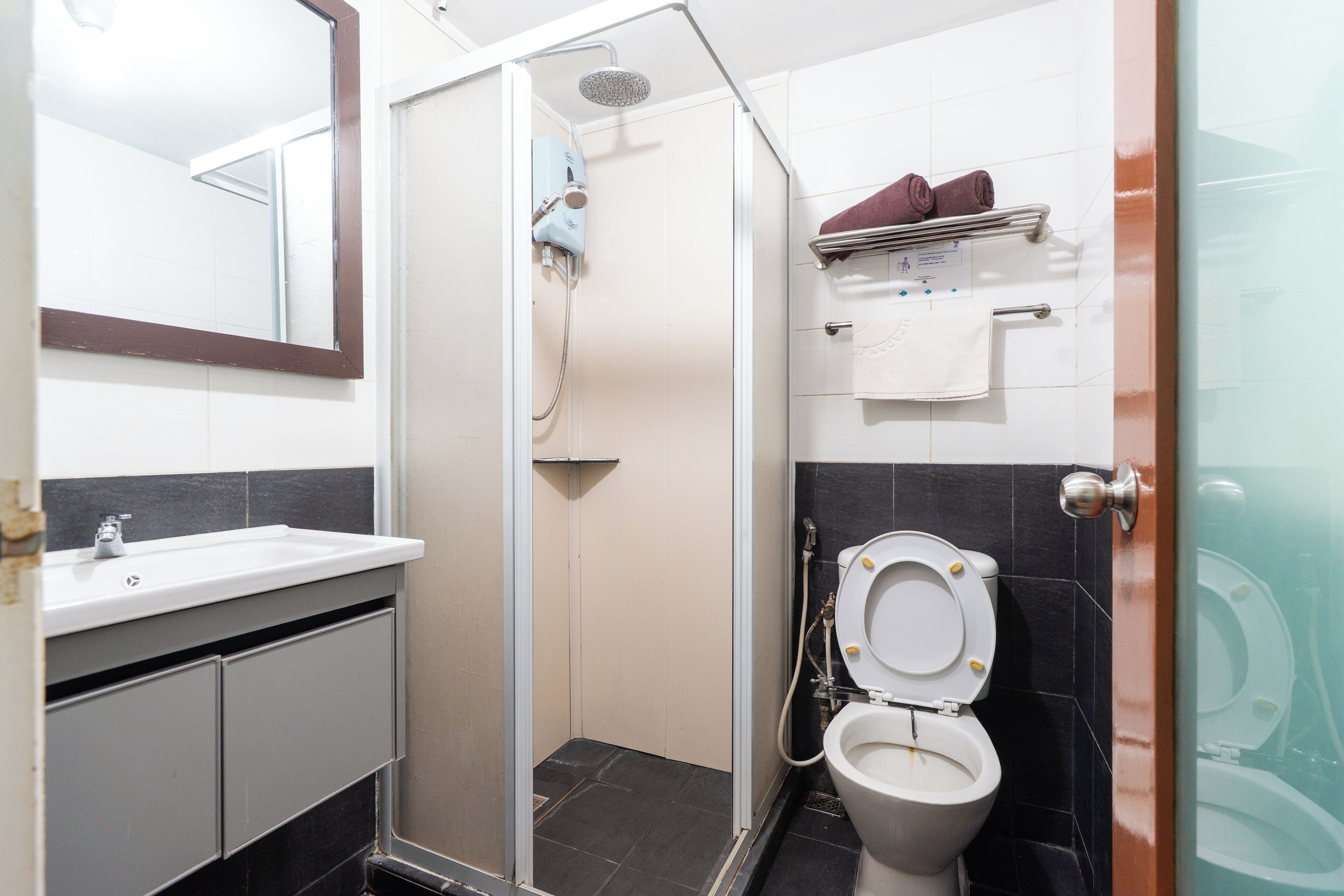 A bathroom with a shower, toilet, sink, and a towel rack with towels.