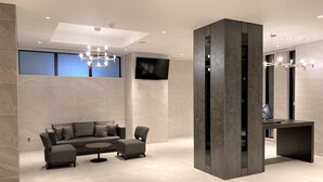 Un vestíbulo moderno con un sofá, una mesa de centro y una pantalla de televisión.