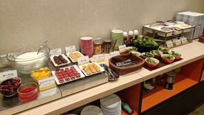 Un bufé con diversas opciones de comida, incluyendo yogur, galletas y ensaladas.