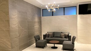 Una sala de estar moderna con un sofá gris, dos sillones y una mesa de centro redonda.