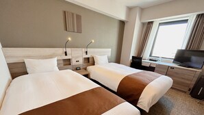 Habitación de hotel con dos camas, televisión, escritorio y ventana con cortinas.