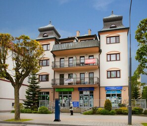 Un immeuble à plusieurs étages doté de balcons, une enseigne indiquant un centre de bien-être et une autre indiquant une agence de voyages.