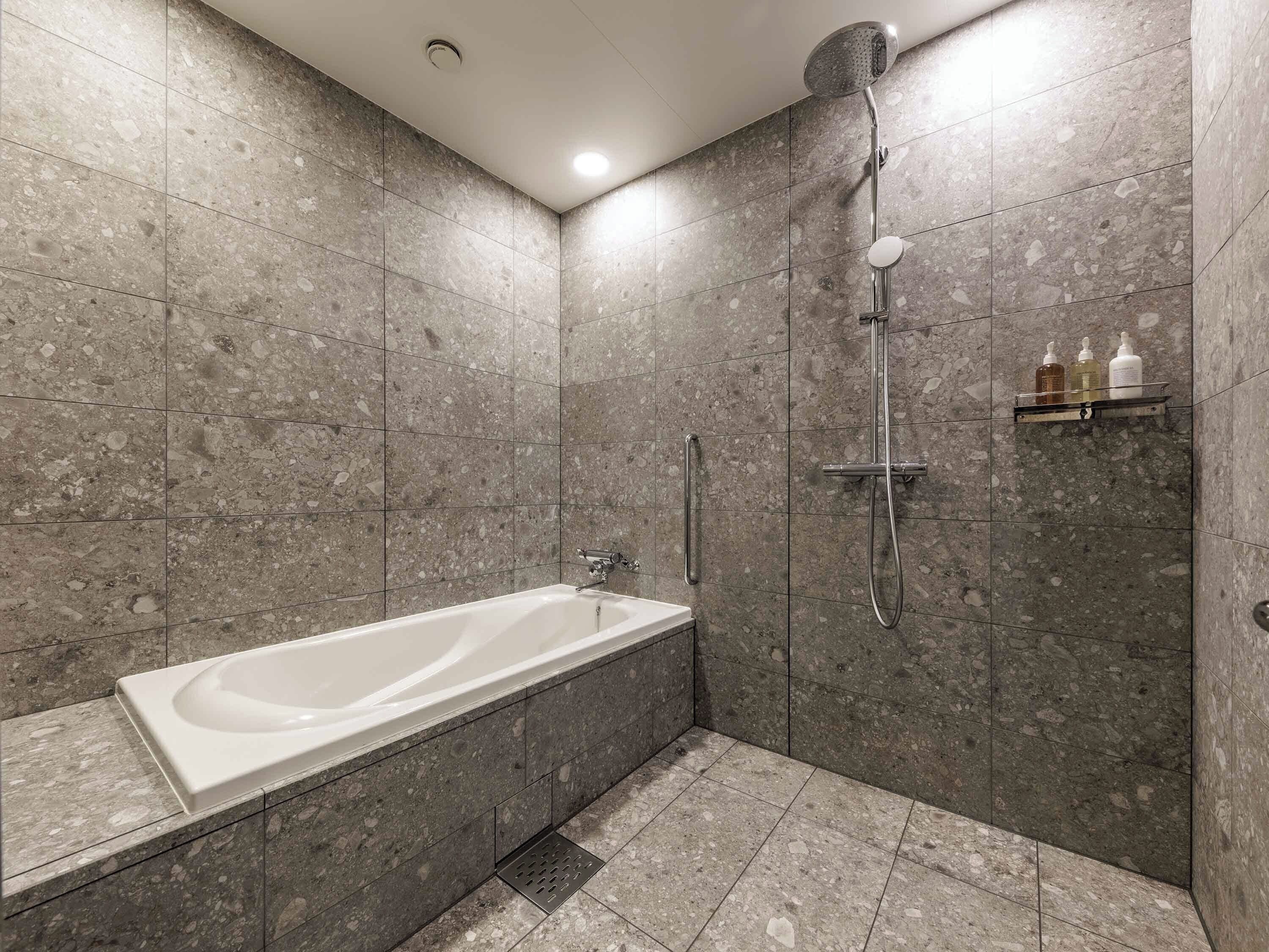A modern bathroom with a freestanding bathtub, a showerhead, and a shelf with toiletries.