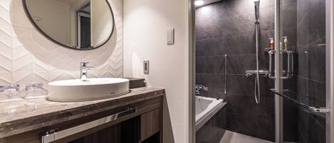 A modern bathroom with a large mirror, a sink, a shower, and a vanity with a towel rack.