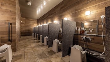 A modern restroom with wooden paneling, individual sinks, and a mirror with hand soap dispensers.
