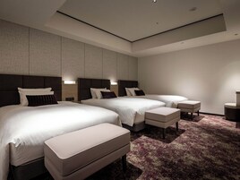 A modern hotel room with two beds, a large window, and a carpeted floor.