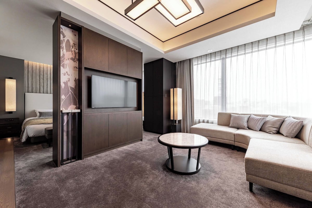 A modern living room with a flat-screen TV, a round coffee table, and a sofa.