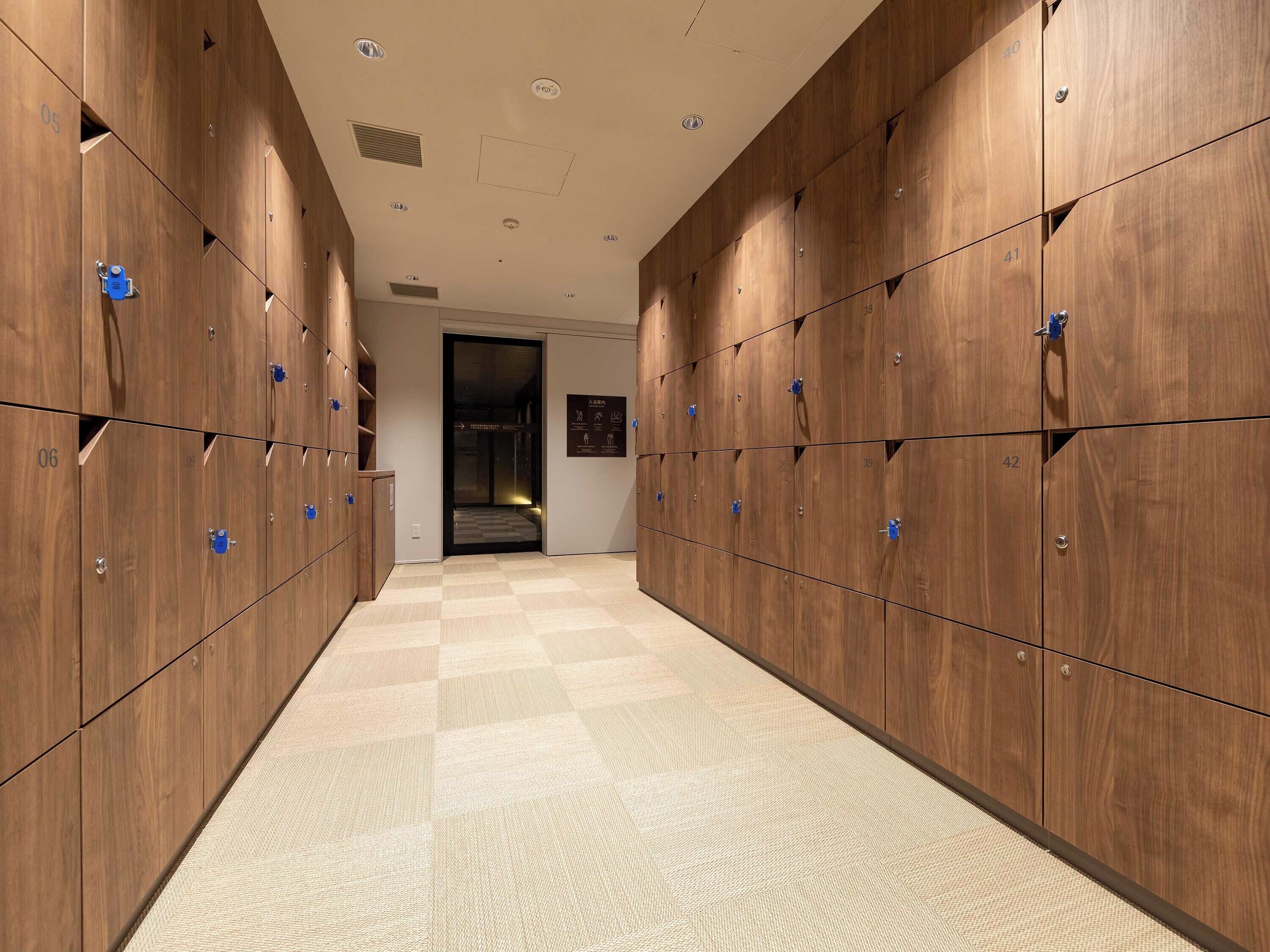 A hallway with wooden lockers numbered 05 to 42, a checkered floor, and a door leading to another room.