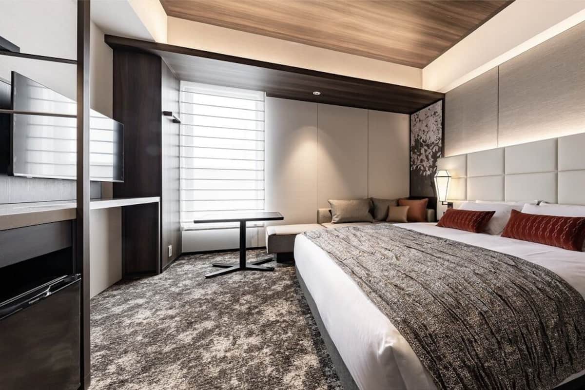 A modern hotel room with a large bed, a desk, and a TV.