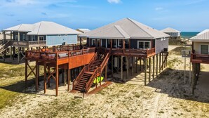 Une propriété située en bord de mer, dotée de structures en bois surélevées, d’un escalier et offrant une vue sur l’océan.