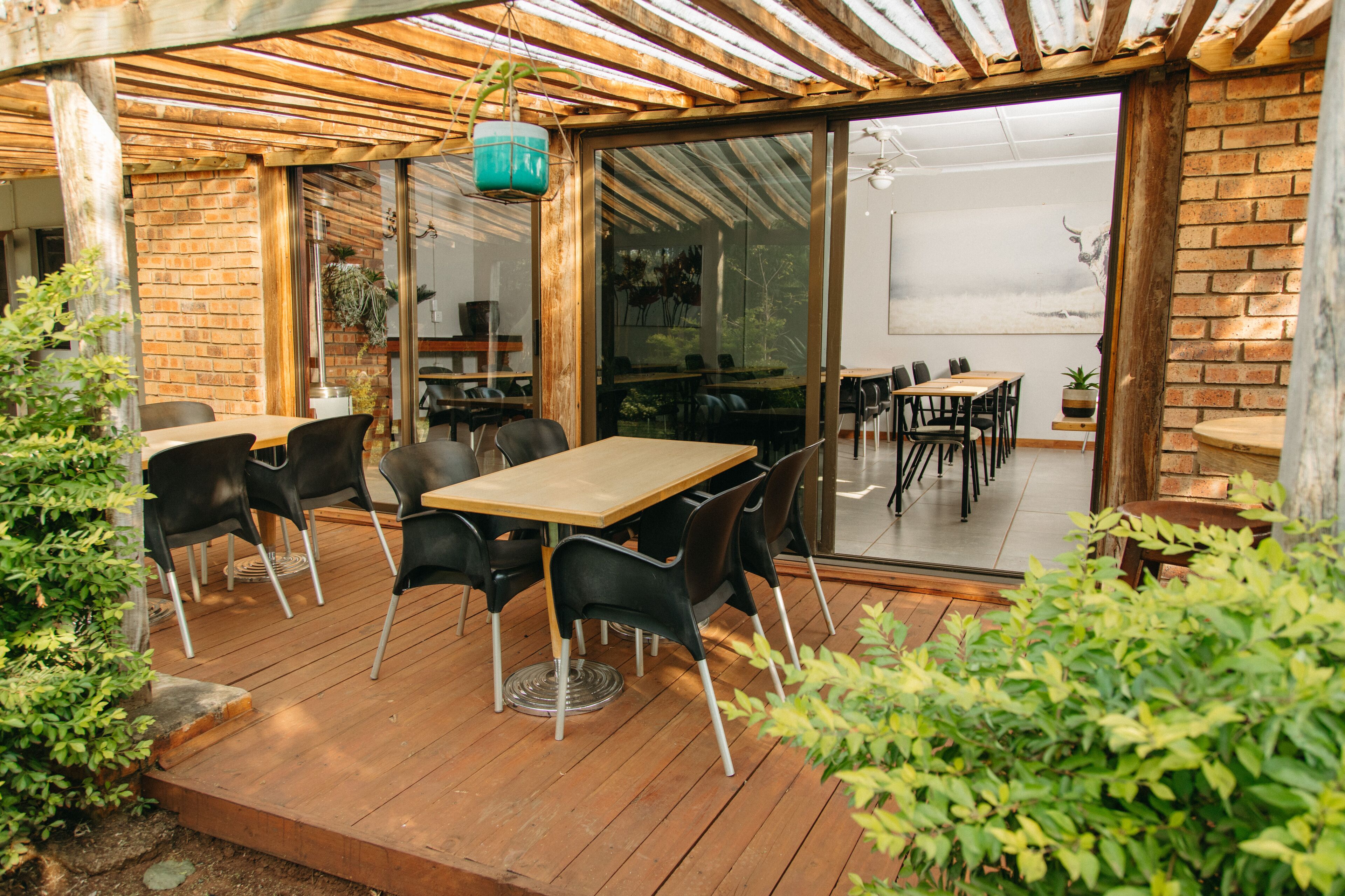 An outdoor patio with wooden flooring, black chairs, and a wooden table.