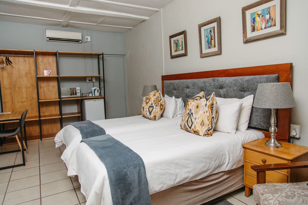 A neatly arranged hotel room with a bed, bedside table, lamp, and a desk with a chair.