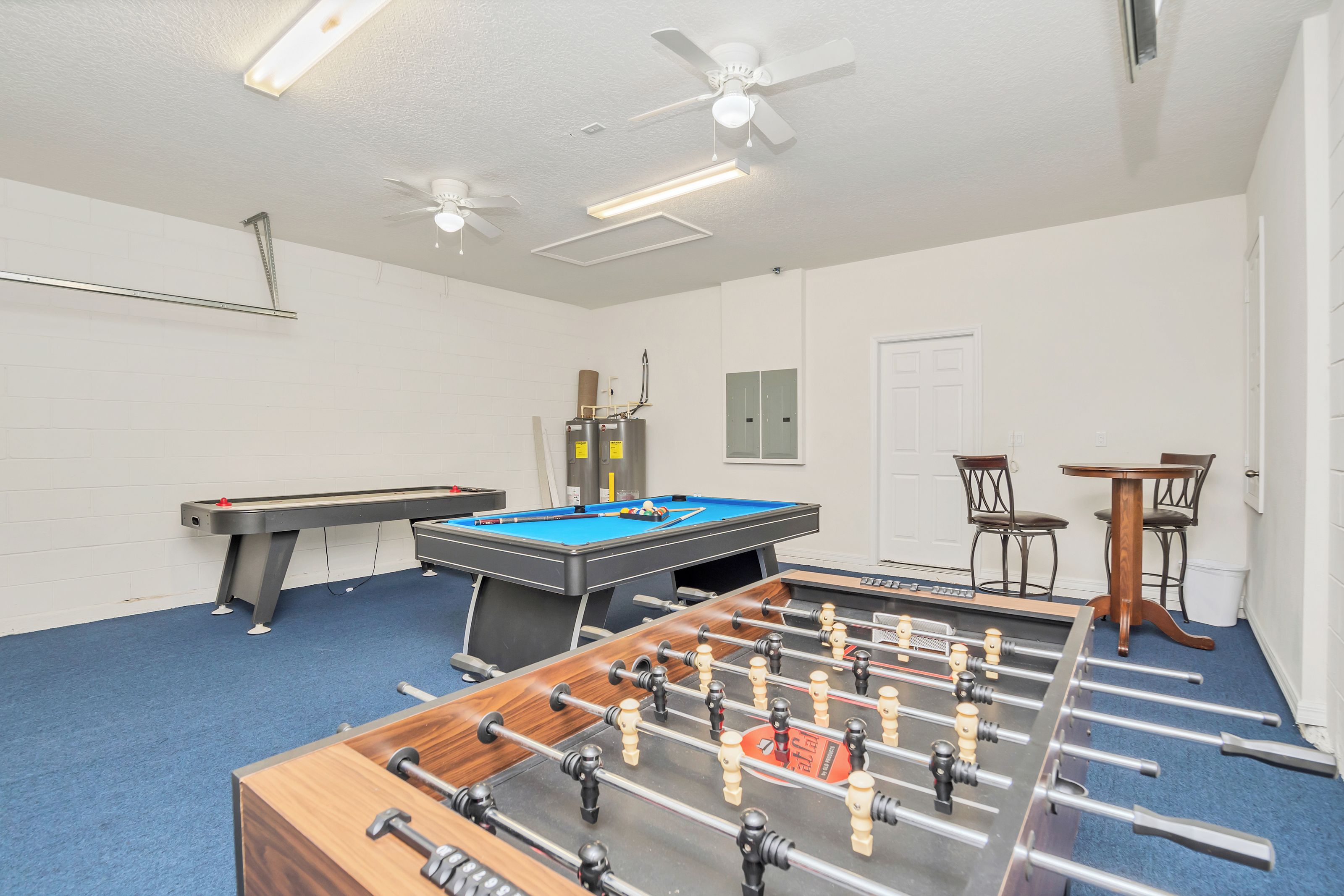 Une pièce équipée d’un baby-foot, d’une table de billard et d’un ventilateur de plafond.