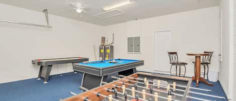 Une pièce équipée d’un baby-foot, d’une table de billard et d’un ventilateur de plafond.