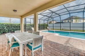 An outdoor patio with a pool, covered seating area, and a view of the neighborhood. - South-Facing Pool • Conservation View • Game Room • No Rear Neighbors • Disney (Davenport)