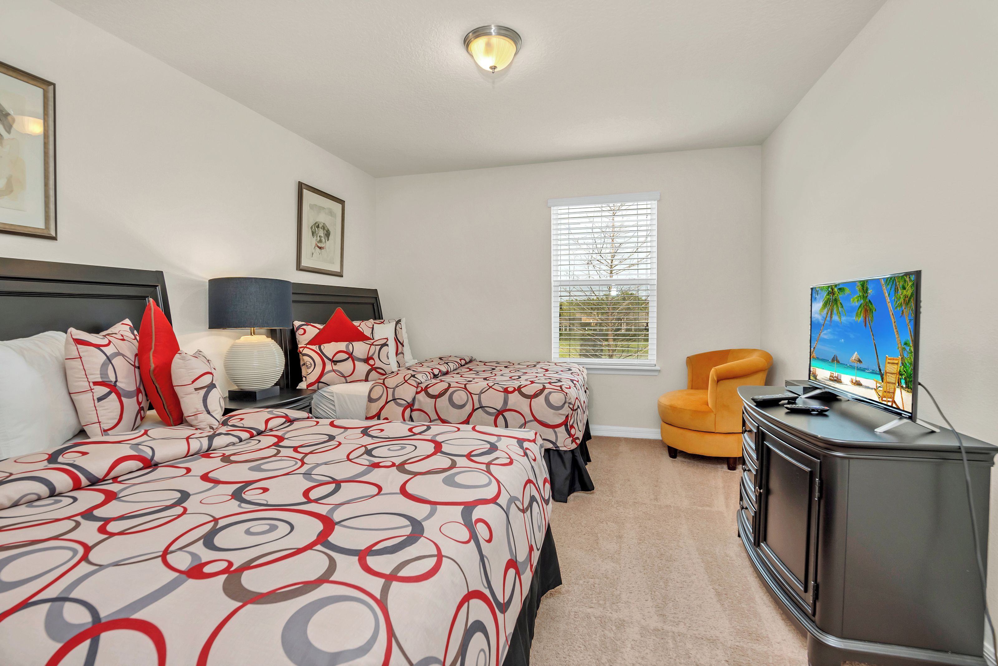Habitación de hotel con dos camas, un escritorio, una silla y un televisor.