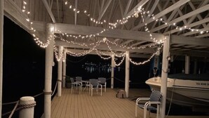 A covered outdoor area with wooden flooring, white railings, and string lights. - Just One More Day: 2 Kayaks, Wifi, Horseshoes, Paddleboard, Panoramic View (Huddleston)