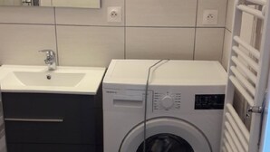A compact laundry room with a washing machine and a sink. - Bright T2 Apartment in La Roche-Posay Center with Wi-Fi and Washer (La Roche-Posay)