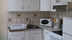 A compact kitchen with white cabinets, a microwave, a coffee maker, and a refrigerator. - Bright T2 Apartment in La Roche-Posay Center with Wi-Fi and Washer (La Roche-Posay)