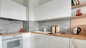 A modern kitchen with white cabinets, a stainless steel oven, a wooden countertop, and a built-in sink. - Flats For Rent - Garden Gates (Gdansk)