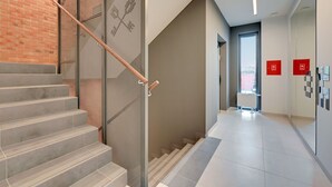 A modern interior with a staircase, a glass partition, and a hallway leading to a door. - Flats For Rent - Garden Gates (Gdansk)