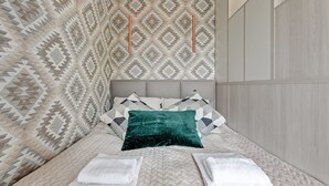 A neatly made bed with patterned wall and a wooden panel wall. - Flats For Rent - Garden Gates (Gdansk)