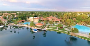 Vista aérea de un resort con una piscina grande, varias construcciones y abundante vegetación.