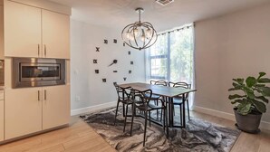 Una cocina moderna con microondas integrado, comedor con mesa y sillas, y un reloj de pared decorativo.