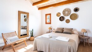 Un dormitorio con una cama grande, un banco de madera, un espejo y adornos en la pared.