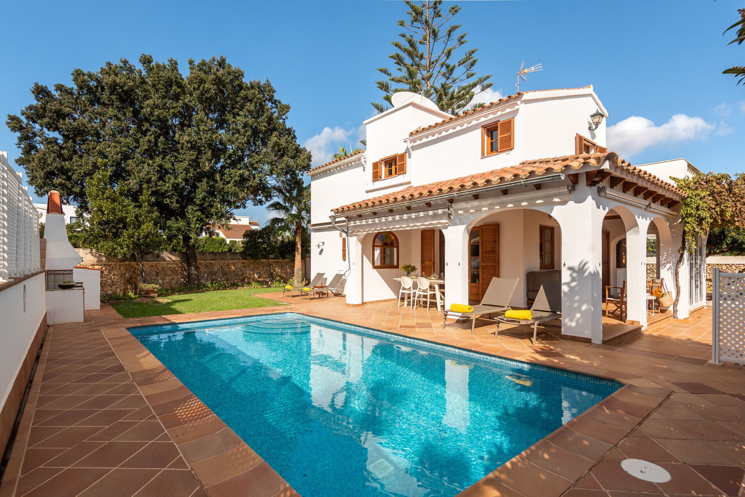 Uma casa de dois andares com piscina, área de estar externa e jardim.