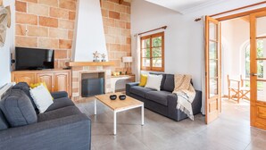 Una sala de estar con pared de piedra, chimenea, televisor y sofá.