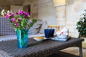 Enjoy a meal or snack in this inviting outdoor seating area with a wicker table and comfortable chair.