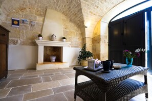 A stone-walled room with a fireplace, wicker furniture, and a view of the outside.